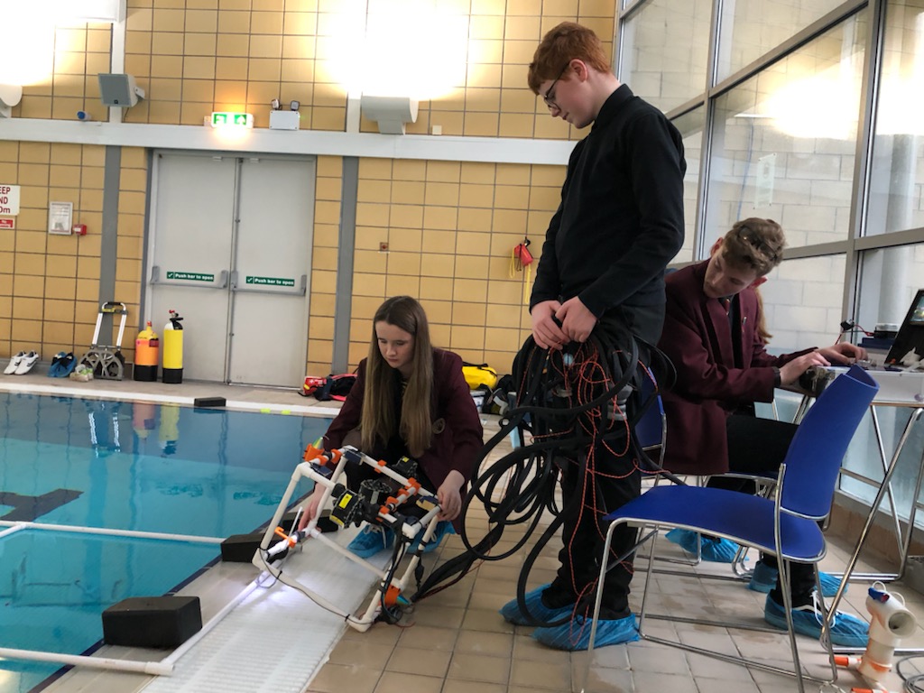 children holding an ROV next to a swimming pool