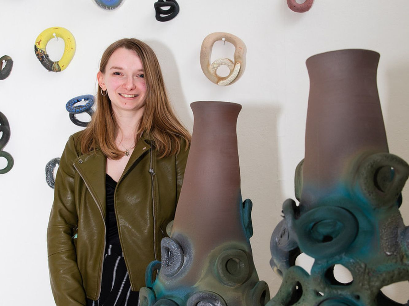 Sinead Calder smiling next to her artwork