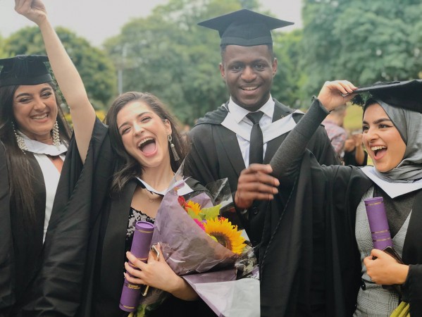 students celebrating with a bunch of flowers at graduation