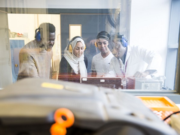 students watching engineering project from behind glass