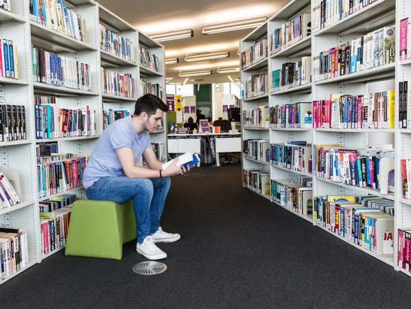 student sitting in the library reading a book student sitting in the library reading a book