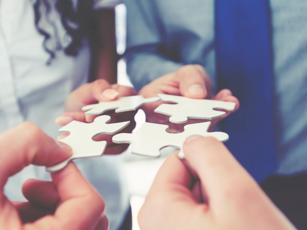 people placing jigsaw puzzle pieces together