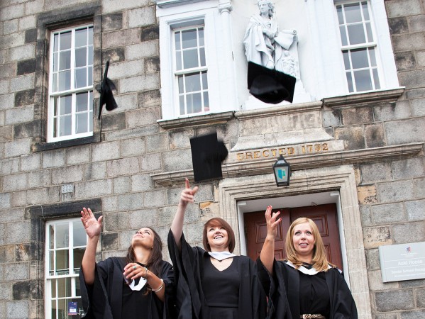 Graduates in gowns throwing their caps in the air Graduates in gowns throwing their caps in the air