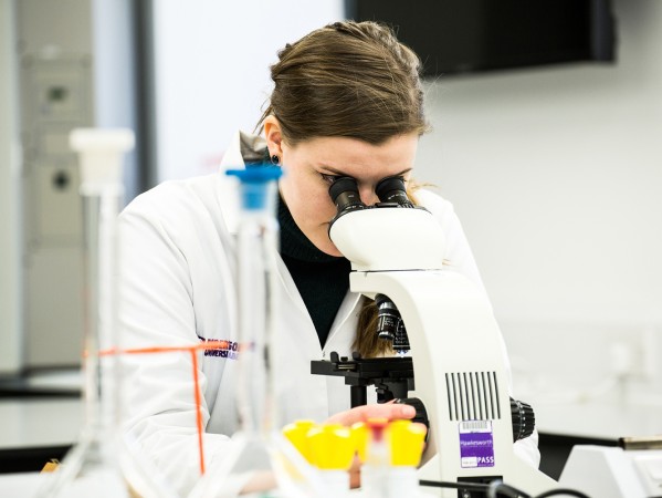 a student looking through a microscope