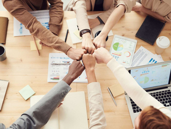 mixed race people fist bumping at a work table mixed race people fist bumping at a work table