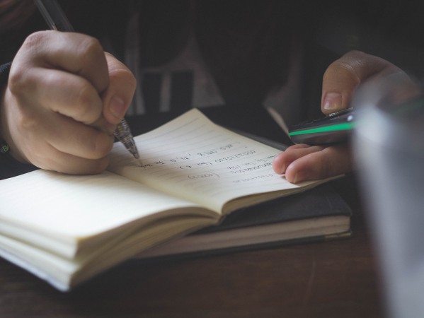 person writing in a notebook person writing in a notebook