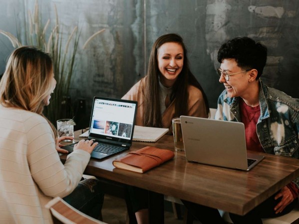 students laughing at a table with laptops